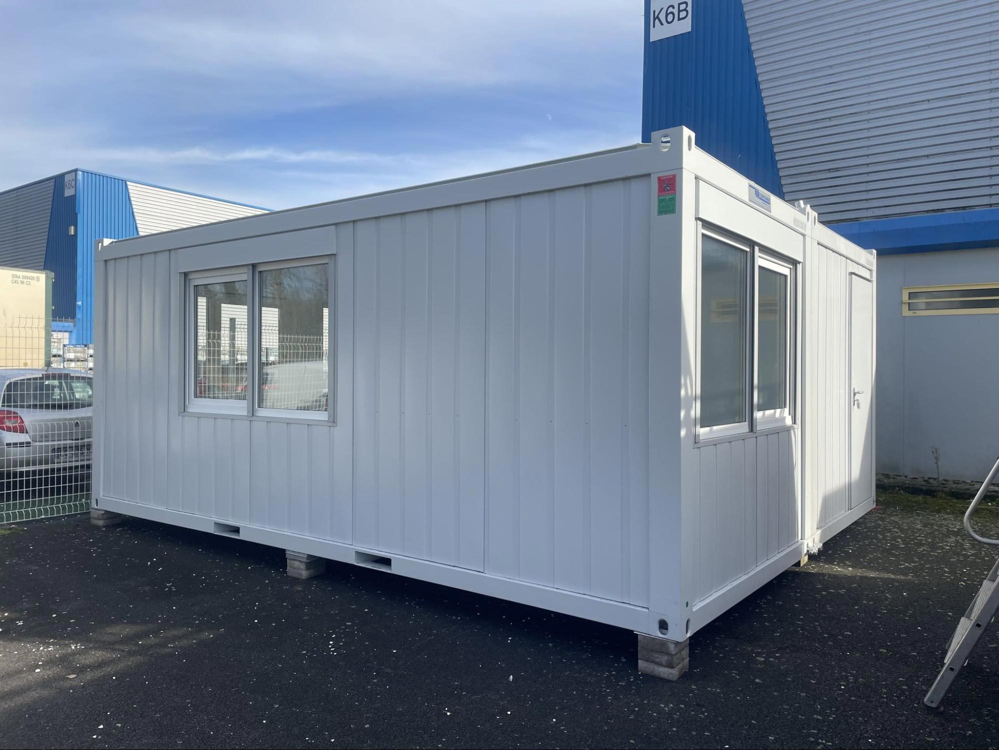 Bâtiment préfabriqué blanc avec deux fenêtres installé comme une extension de bureau