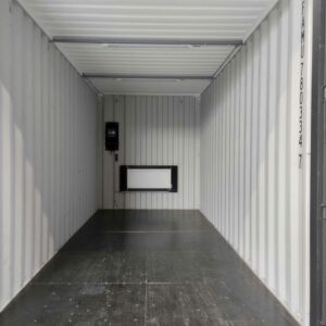 Intérieur aménagé d’un container transformé en local technique avec radiateur et réseau électrique.