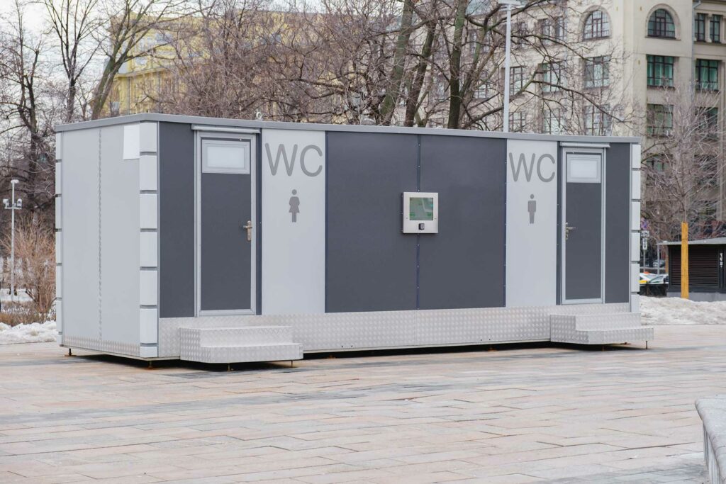 Bloc sanitaire préfabriqué double avec accès surélevé, installé dans un espace public urbain